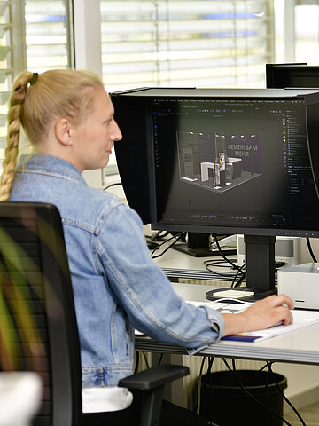 Mitarbeiterin aus der Grafik-Abteilung beim erstellen einer 3D Vorschau eines Messebau für einen Kunden